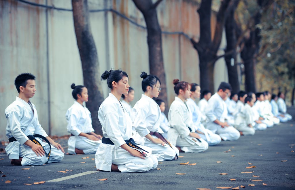 Group of martial artists practicing meditation and focus outdoors, dressed in traditional gis.